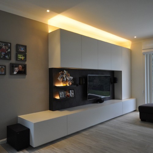 Les habitants de cette maison étaient à la recherche d’un meuble TV unique. L’éclairage à variation d’intensité que nous avons intégré (tant au niveau du plafond que des étagères) dé